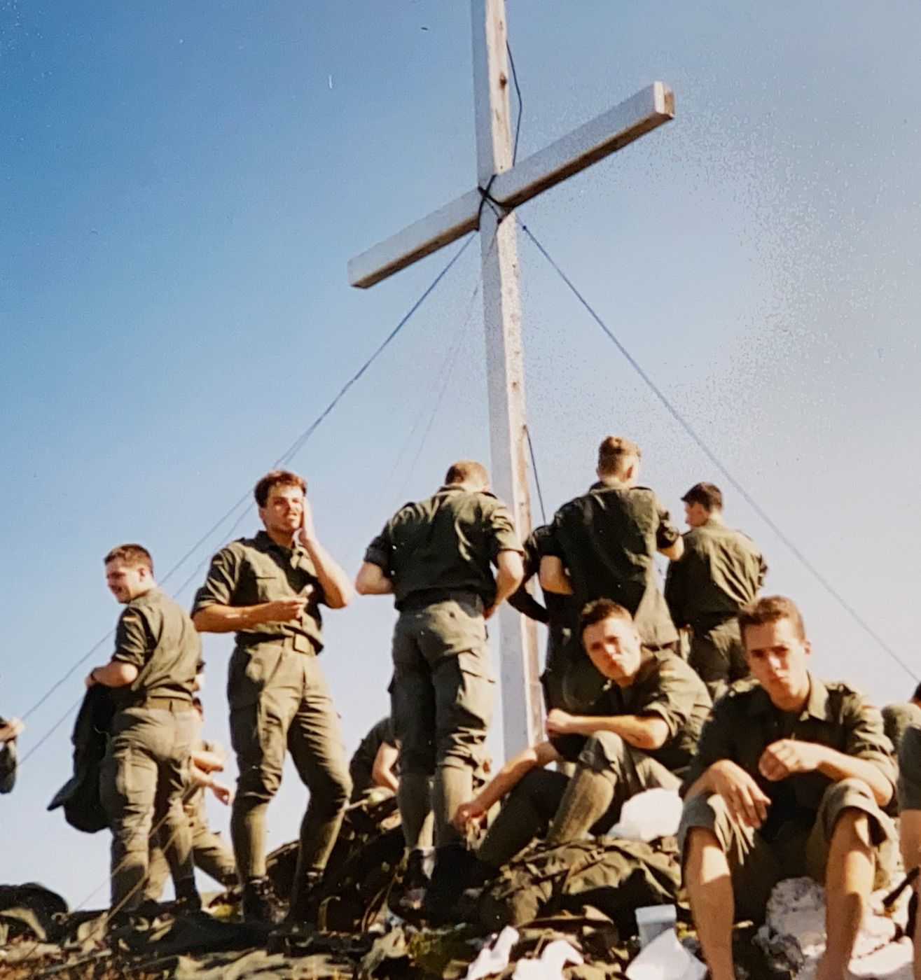 Soldaten rasten während einer Bergausbildung an einem Gipfelkreuz